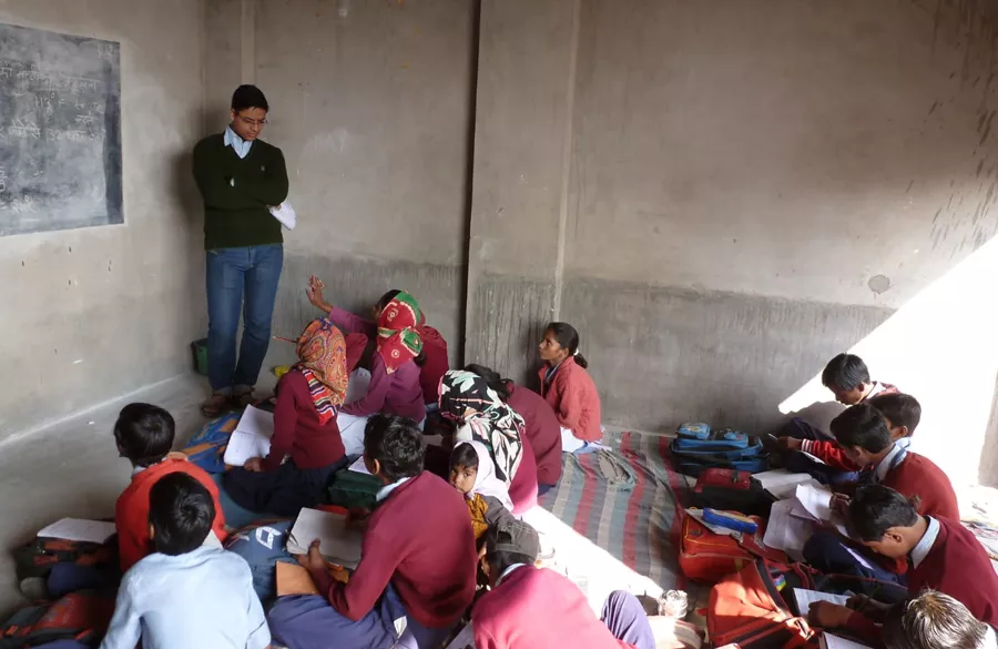 Volunteer teaching English to children in a Jaipur village classroom