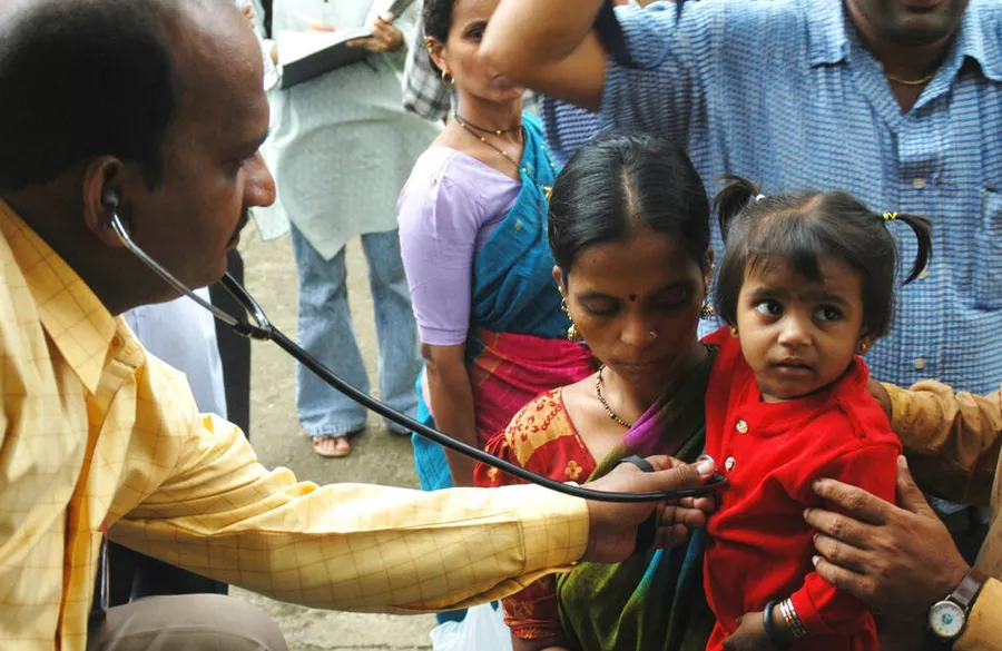 Local doctor and volunteer checking blood pressure at camp